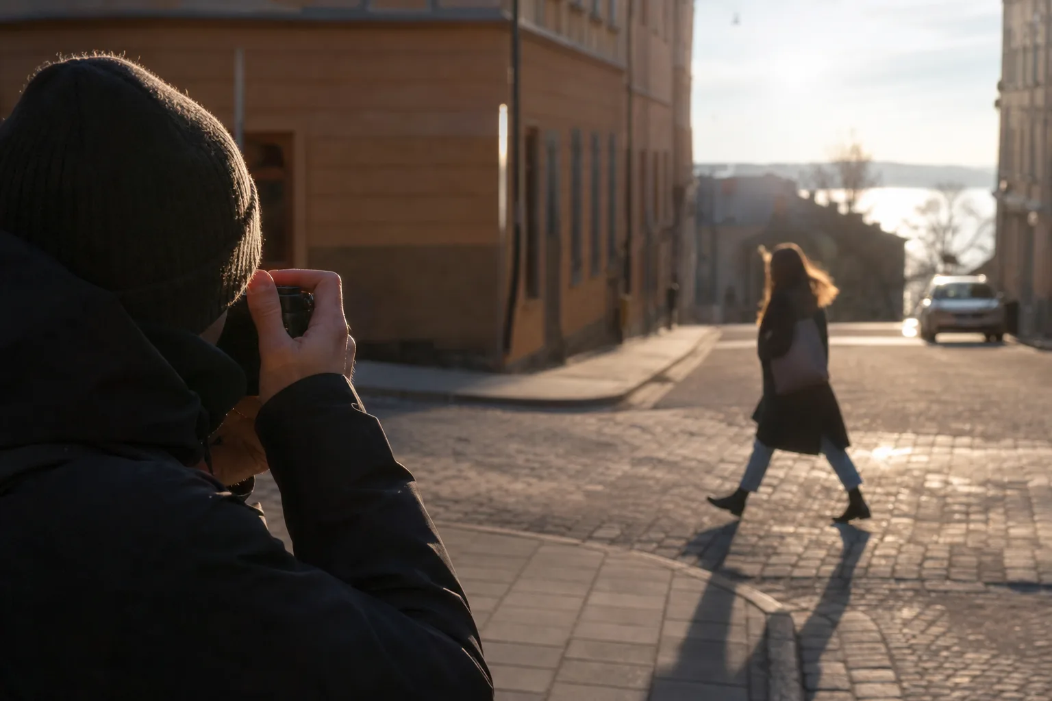 Gatufotografering av en person som passerar över en solbelyst gata, fångad med en diskret kamera
