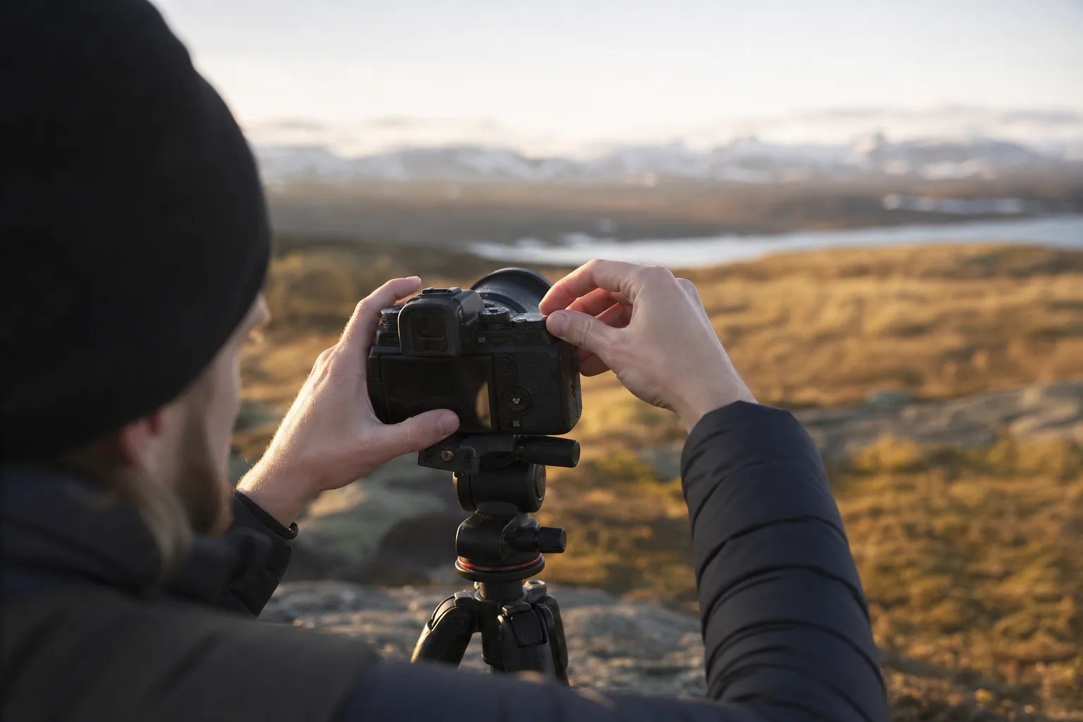 Fotograf justerar bländare och slutartid för hand på ett kamerahus i morgonljus