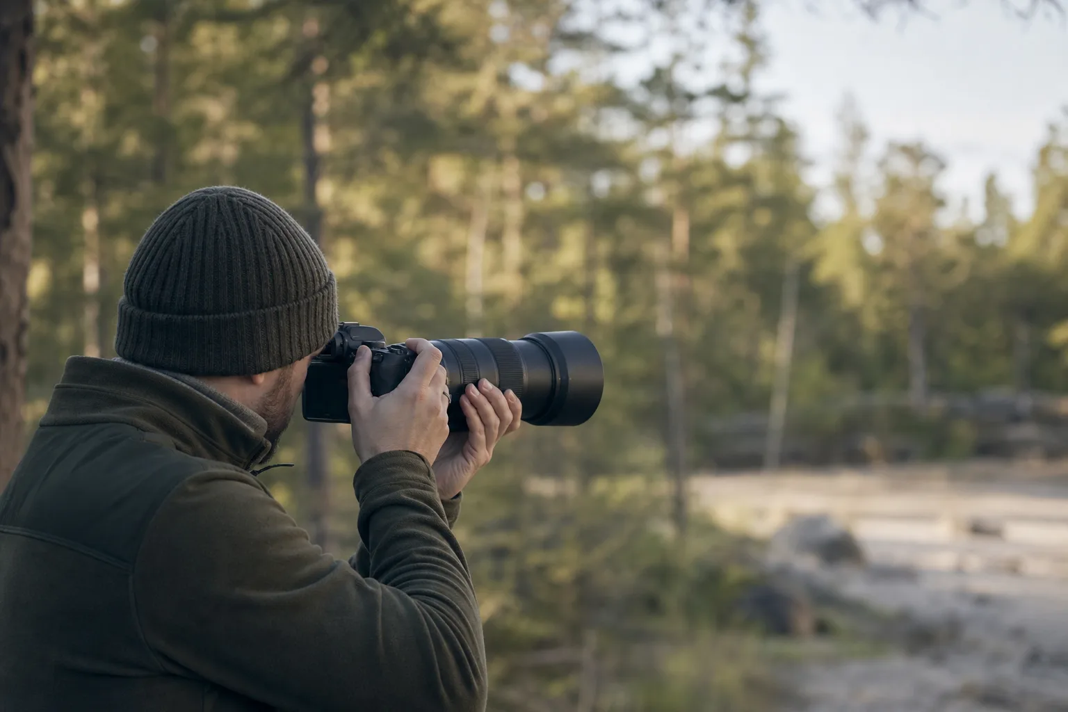 Fotograf håller ett kamerahus stadigt med ett teleobjektiv i naturmiljö